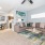 Spacious and well lit living room with wood flooring, large windows and open access to the kitchen